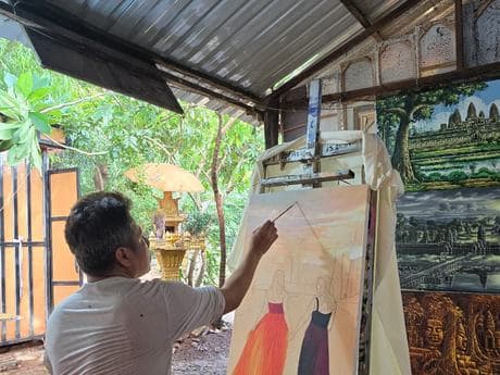 A Velea artist painting a commissioned portrait at an outdoor easel.