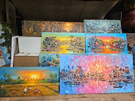 Finished oil paintings stacked in the studio, drying.