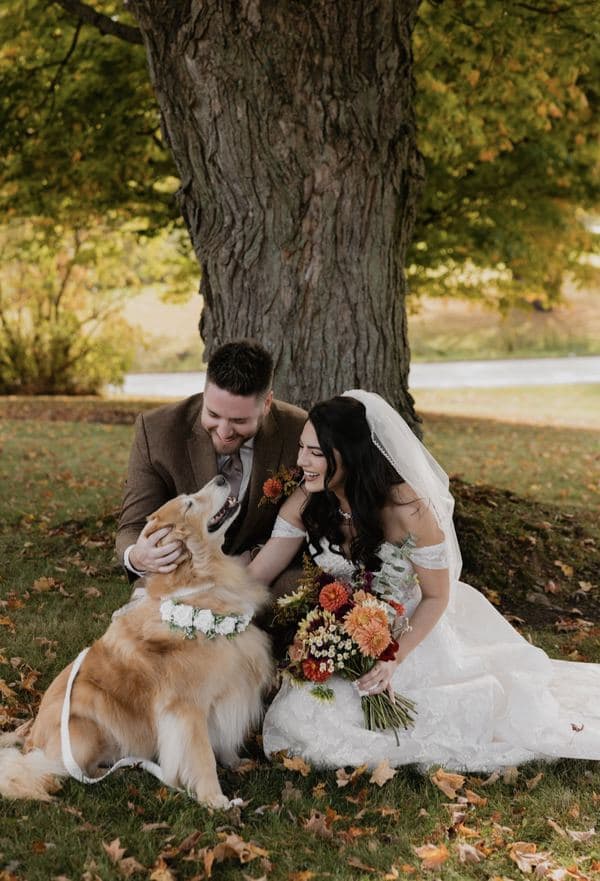 The original wedding photograph: a bride and groom laughing with their dog, who is wearing a flower collar.